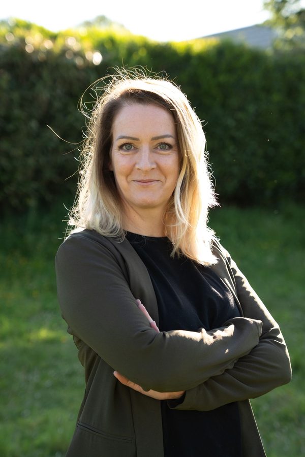 Portrait d'Anne-Cécile Le Dain, bras croisés, dans un jardin